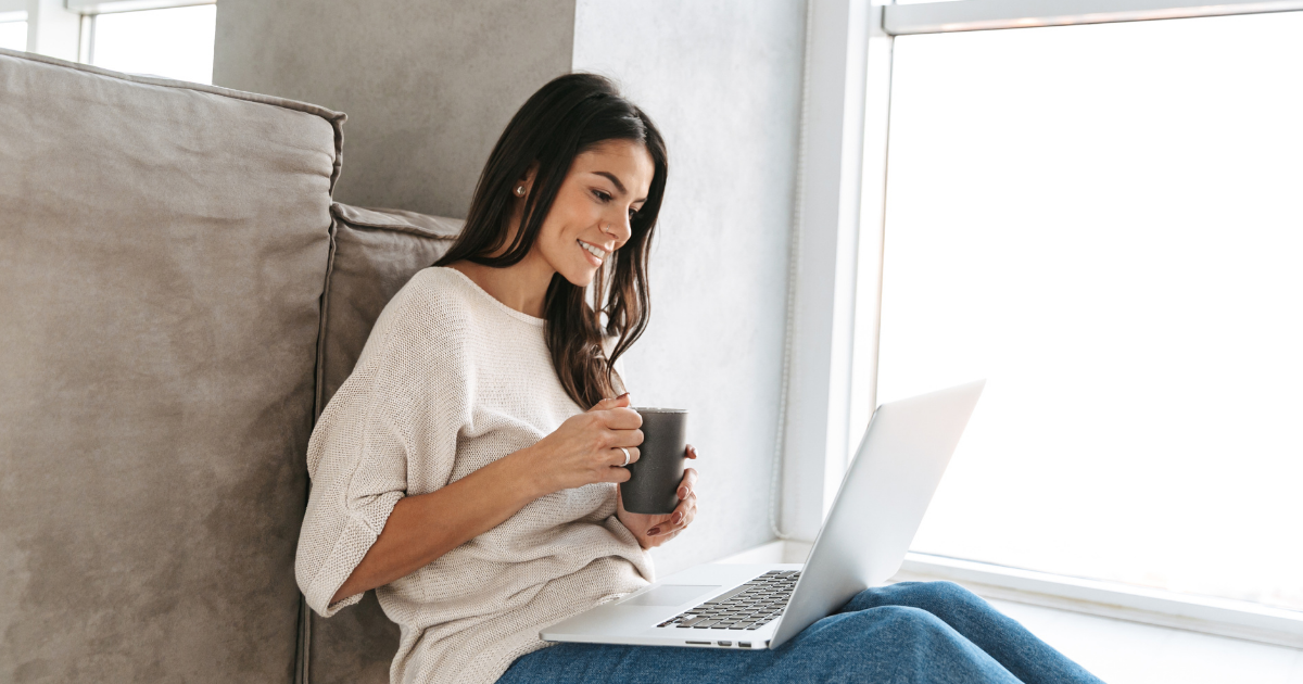 Smiling woman with a cup of coffee and a laptop